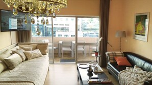 A living room with a sofa, a coffee table, and a TV mounted on the wall. - QUAD 2 with Balcony, Garage, A.C. (Cold or heat), 24/7 security  (Lisboa)