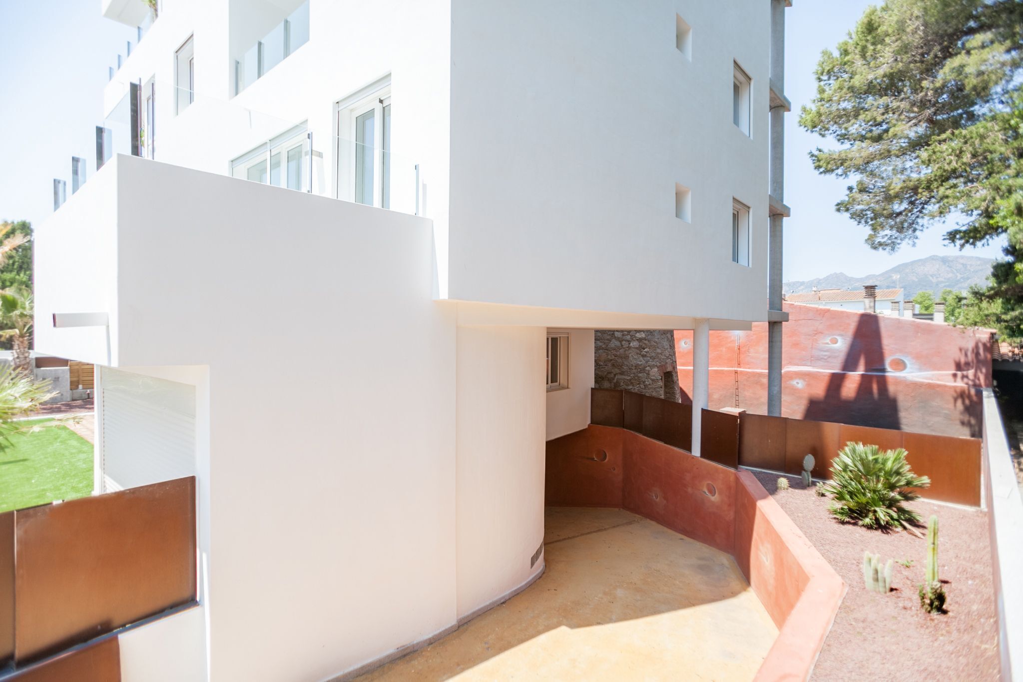 Un edificio moderno con un cortile interno, caratterizzato da un mix di pareti bianche e rosse e una piccola zona giardino con cactus.