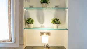 A corner with a glass shelf holding potted plants and a table lamp. - Ve.N.I.Ce. Cera Casa Santo Stefano  (Venezia)