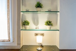 A corner with a glass shelf holding potted plants and a table lamp. - Ve.N.I.Ce. Cera Casa Santo Stefano (Venezia)