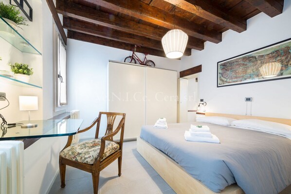 A bedroom with a bed, a chair, a glass table, a wardrobe, and a bicycle on the wall. - Ve.N.I.Ce. Cera Casa Santo Stefano (Venezia)