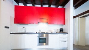 A modern kitchen with white cabinets, a stainless steel oven, and a red upper cabinet. - Ve.N.I.Ce. Cera Casa Santo Stefano  (Venezia)