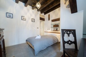A bedroom with a bed, a chair, a shelf with items, and a framed picture on the wall. - Ve.N.I.Ce. Cera Casa Santo Stefano  (Venezia)