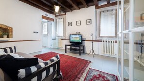 A living room with a fireplace, a television, and a red rug. - Ve.N.I.Ce. Cera Casa Santo Stefano  (Venezia)