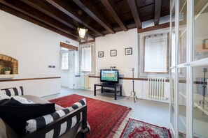 A living room with a fireplace, a television, and a red rug. - Ve.N.I.Ce. Cera Casa Santo Stefano  (Venezia)