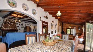 A dining area with a patterned tablecloth, wooden chairs, and a central table with a basket of fruits. - Ses Rodes, holiday villa in Porto Colom, Mallorca (Felanitx)