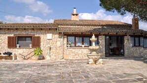 A stone building with a tiled roof, a fountain, and a small garden area. - Ses Rodes, holiday villa in Porto Colom, Mallorca (Felanitx)