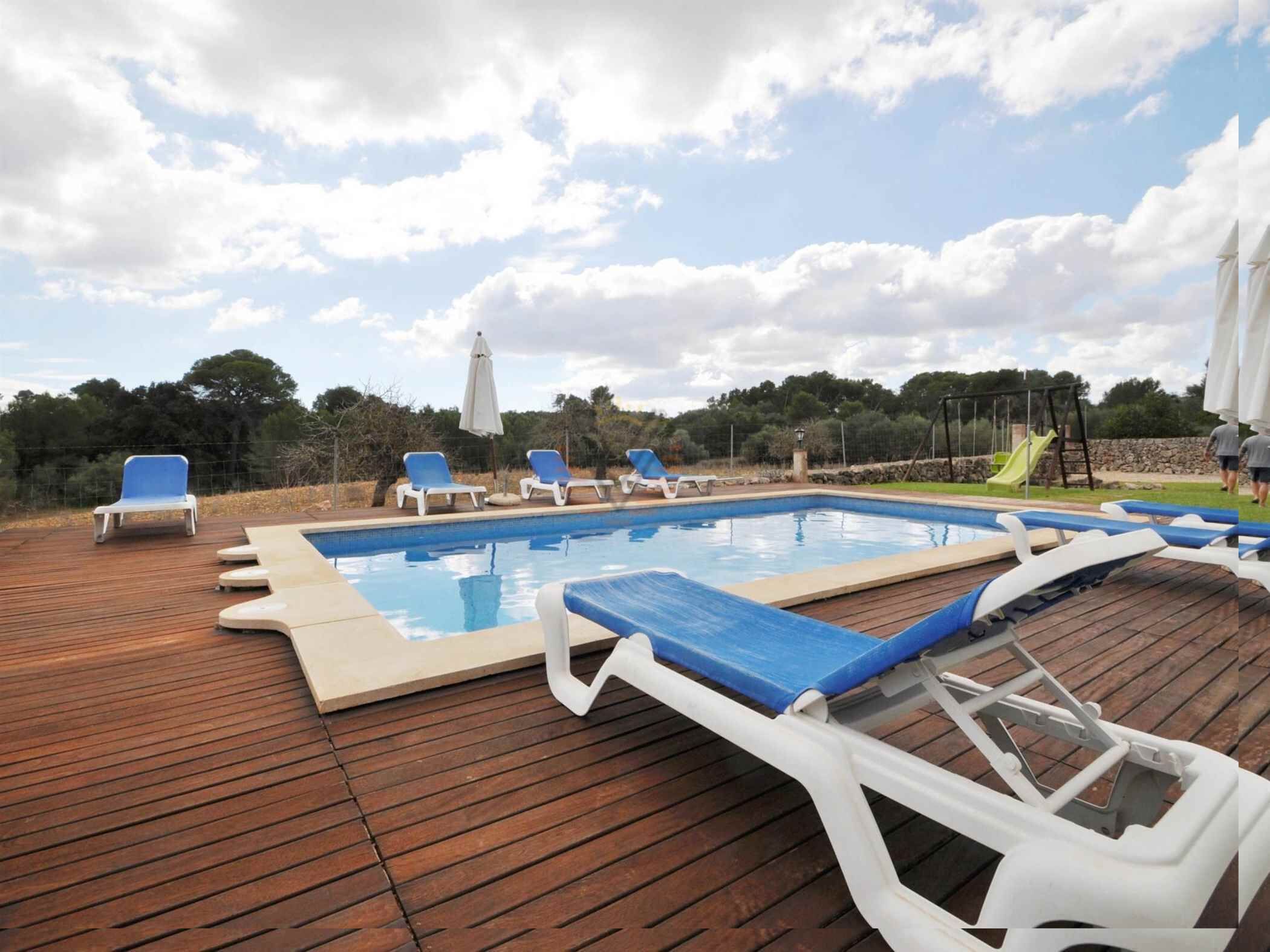 A swimming pool with lounge chairs and a wooden deck.
