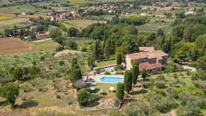 Una vila amb piscina, envoltada d'oliveres i vinyes, situada en un paisatge rural.