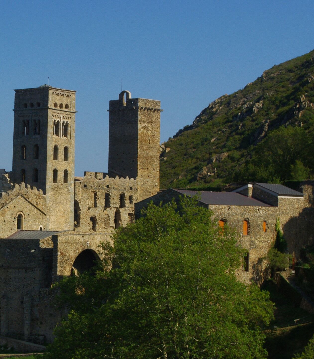 A historic stone building with two towers, one with a balcony and the other with a flat roof.