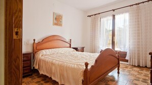 A bedroom with a wooden bed, a nightstand, a dresser, and a window with curtains. - Villa with private swimming pool.HUTG-015590 (l'Escala)