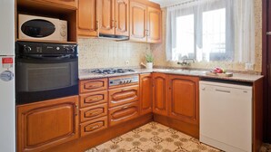 A kitchen with wooden cabinets, a built-in oven, a dishwasher, and a window with curtains. - Villa with private swimming pool.HUTG-015590 (l'Escala)