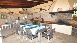 An outdoor dining area with stone walls, a brick fireplace, and rustic furniture. - Casa Antonio: Rural Charm with Pool (Buger)