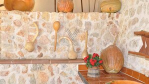 A rustic kitchen with stone walls, wooden utensils, and a potted plant. - Casa Antonio: Rural Charm with Pool (Buger)