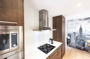 A modern kitchen with stainless steel appliances, a cityscape mural, and wooden cabinetry.