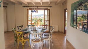 Un comedor con una mesa dispuesta para seis personas, rodeada de sillas, vistas de la ciudad a través de amplias ventanas y un cuadro en la pared.