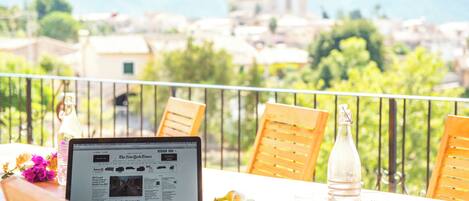 A laptop on a balcony with a view of a historic building and mountains.