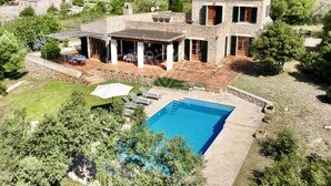 A two-story stone house with a swimming pool, outdoor seating, and a view of the surrounding countryside. - Charming Mallorcan house with beautiful views (Son Servera)