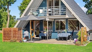 A two-story house with a balcony, a covered patio area, and a well-maintained lawn. - 3 bedroom gorgeous home in Rudkøbing (Rudkøbing)