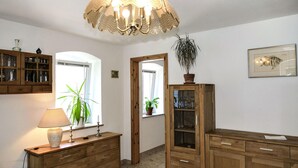 Een kamer met houten meubels, een kroonluchter, een potplant en een lijst met een afbeelding aan de muur.