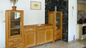 Een houten kast met glazen deuren, een plant in pot en een lijst met afbeelding aan de muur.
