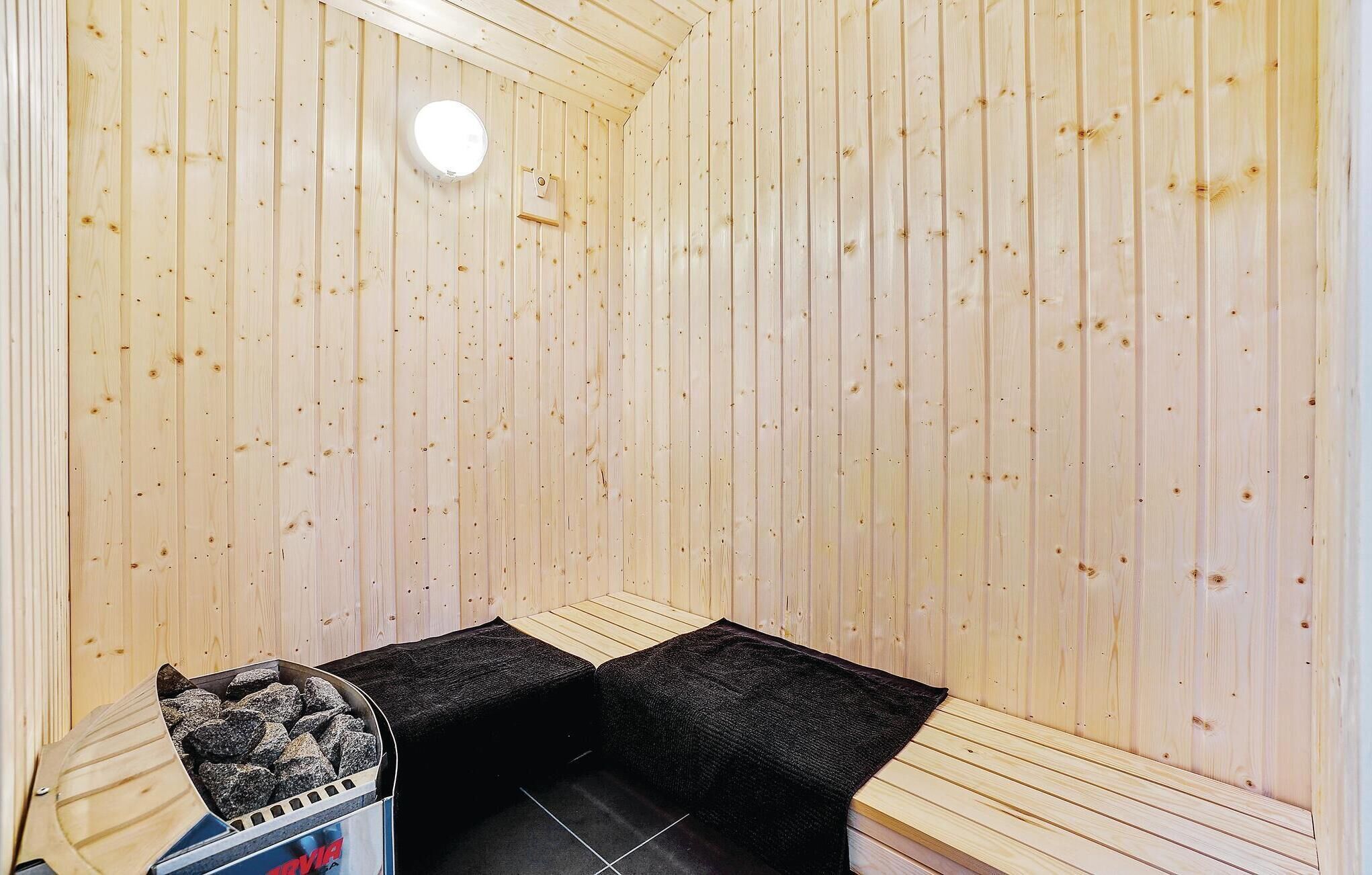 Ein Saunaraum mit Holzwänden, einer Sitzbank und einem mit Steinen gefüllten Ofen.