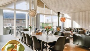 A spacious dining area with a long table, multiple chairs, and a large window offering a view of the outdoors. - 4 bedroom nice home in Odder (Odder)