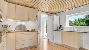 Una cocina moderna con armarios de madera, horno integrado y ventana con vistas a la vegetación.