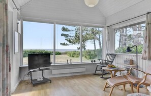 A sunroom with a TV, seating, and a view of the outdoors. - 2 bedroom nice home in Slagelse (Slagelse)