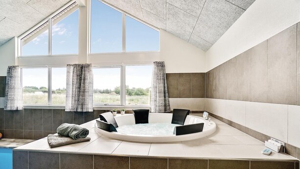 Un baño moderno con una bañera independiente, ventanas amplias y vistas al exterior.