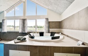 A modern bathroom with a freestanding bathtub, large windows, and a view of the outdoors.
