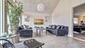 Una sala de estar moderna con dos sofás, una mesa de centro y una planta grande en maceta.