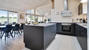 Una cocina moderna con una isla grande, muebles oscuros y un horno empotrado.