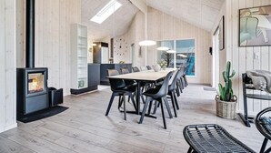 Una cocina moderna con estufa integrada, paredes de madera y un comedor con una mesa larga y sillas.