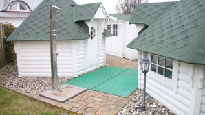 A white building with a green roof and a small porch area with a green mat. - Exclusive apartment with garden and fireplace near the beach (Zingst)