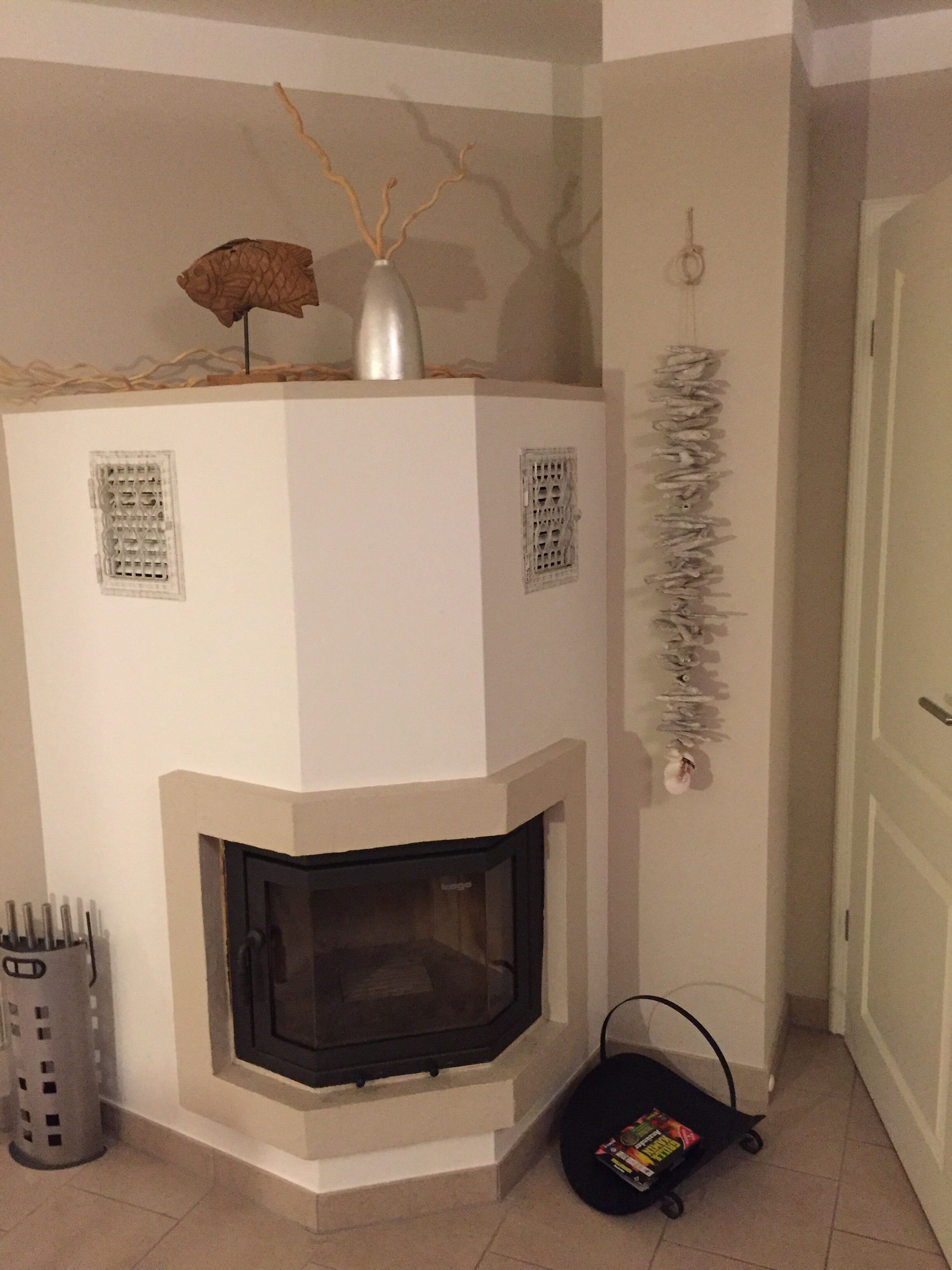 A modern fireplace with a white mantel, a decorative vase, and a small table on top.