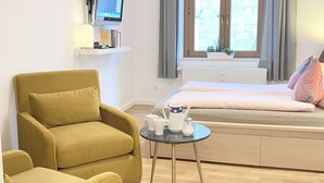 A modern living room with a sofa, two yellow armchairs, a small round table with a teapot, and a television on a shelf. - Apartment in the heart of Boppard (Boppard)