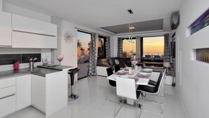 A modern kitchen with white cabinets and a dining area with a table set for four. - Modern Villa Nera with pool and sea view, three bedrooms 6+2 people (Makarska)