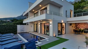 A modern two-story house with a swimming pool, outdoor seating, and a dining area. - Modern Villa Nera with pool and sea view, three bedrooms 6+2 people (Makarska)
