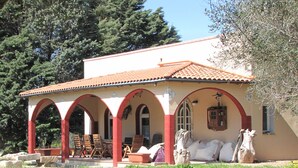 A two-story building with a red-tiled roof, multiple arches, and a garden in the foreground.