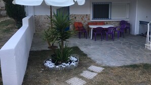 A patio area with a white umbrella, a small potted plant, and a table with purple chairs. - Calista Luxury Appt (Kassandra)