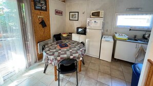 A compact kitchen with a dining table, chairs, a microwave, a refrigerator, and a small sink.