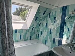 A bathroom with a skylight, a bathtub, and a sink.