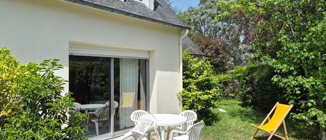 A house with a patio, a table with chairs, and a yellow chair.