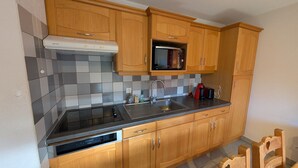 Cucina con mobili in legno, forno a microonde, lavello e lavastoviglie.