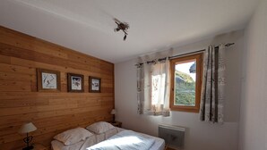 Una camera da letto con testiera in legno, un letto con biancheria bianca, un comodino con una lampada e una finestra con tende.