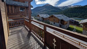 Una baita di legno con un balcone affacciato su un paesaggio montuoso.