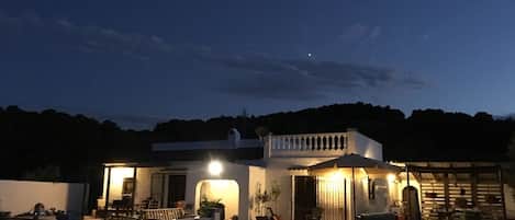 Une maison moderne dotée d’une piscine, d’un patio couvert et offrant une vue sur les collines environnantes.