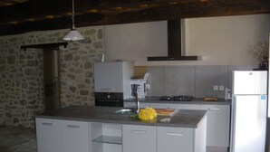 Eine moderne Küche mit Kochinsel, Steinwand und eingebauten Geräten.