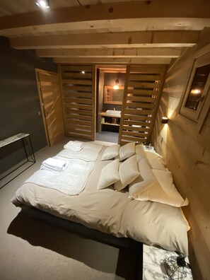 A bedroom with a bed, wooden slats, a nightstand, and a small table.